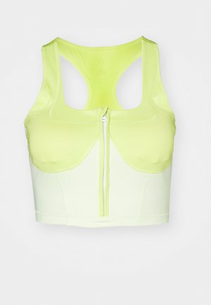Yellow sports bra with a zip front, featuring a racerback design and contrasting fabric texture. Made from stretchy, moisture-wicking material.