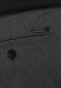 Tessuto di colore grigio scuro con motivo a quadri, dettaglio con bottone nero e un piccolo etichetta del marchio che riporta "JACK & JONES."