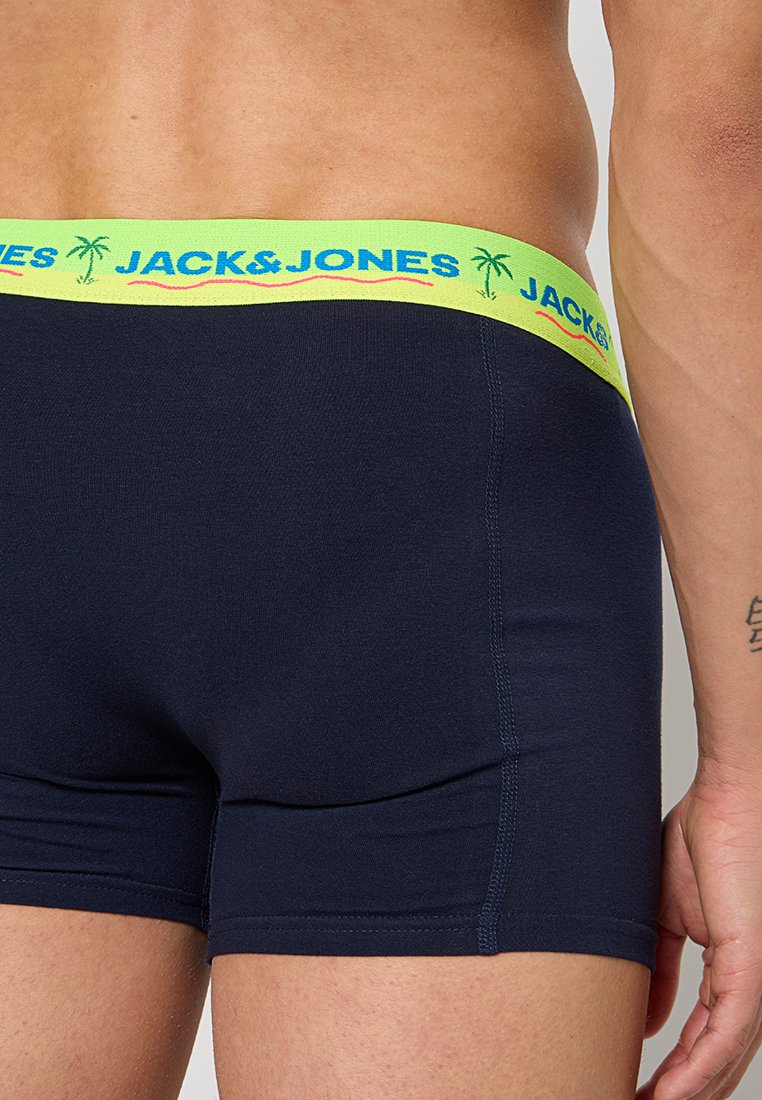 Homme portant un slip boxer bleu marine avec une ceinture vert fluo portant le texte "JACK & JONES" et des icônes de palmier.