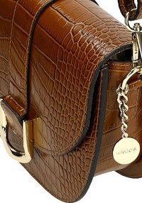 Bruine nep-krokodillenlederen handtas met een klep-sluiting, goudkleurige details, en een ketting accent met een ronde tag. Glad textuur.
