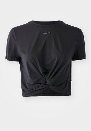 Crop top de sport noir en tissu doux, avec un design à nœud à l'avant et des manches courtes, portant un petit logo Nike gris au niveau du col.