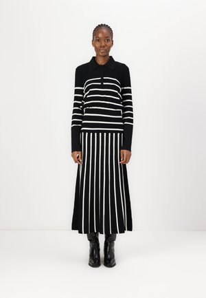 Top a maniche lunghe con colletto a righe bianche e nere abbinato a una gonna maxi a righe coordinate. Il materiale sembra morbido con una vita aderente.