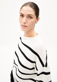 Schwarz-weißer gestreifter Pullover mit Bootsausschnitt und lockerer Passform. Der Stoff wirkt gerippt und betont die auffälligen Streifen und die Textur.