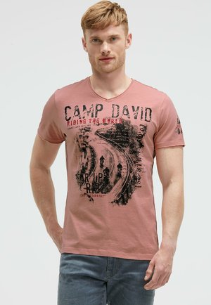 Rosa Baumwoll-T-Shirt mit V-Ausschnitt und kurzen Ärmeln, das einen schwarzen Grafikdruck mit Text und einem Design von gewundenen Straßen zeigt.