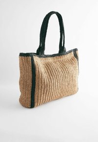 Geweven draagtas van tan kleurig stro met zwart geweven handvatten en rand, met een textuur van ribbelpatroon en een ruime vormgeving.