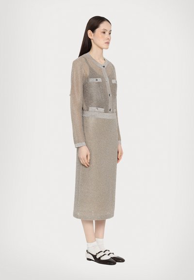 Vestido largo de punto en gris metálico con un cuerpo ajustado, cierres de botones y bolsillos de parche. Acentuado con ribetes y puños en contraste.