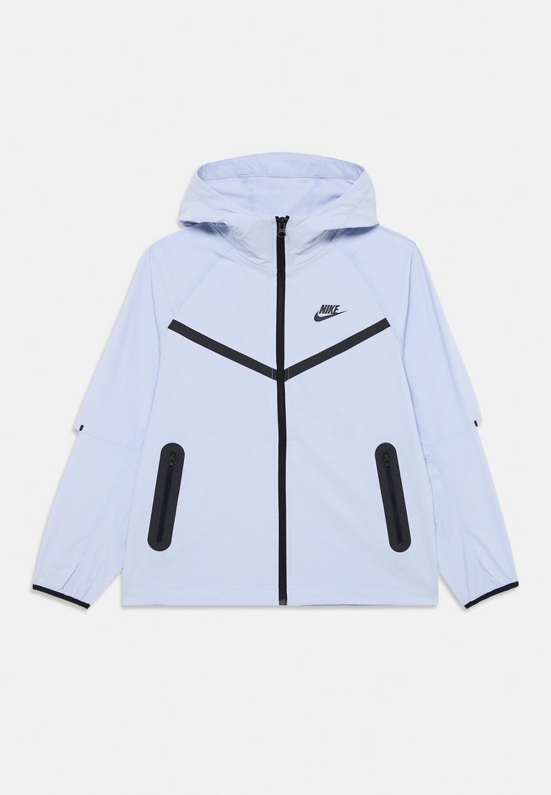 Ljusblå Nike-jacka med huva, med en svart dragkedja framtill, svarta detaljer och två sidfickor med dragkedja. Slät tygtextur.