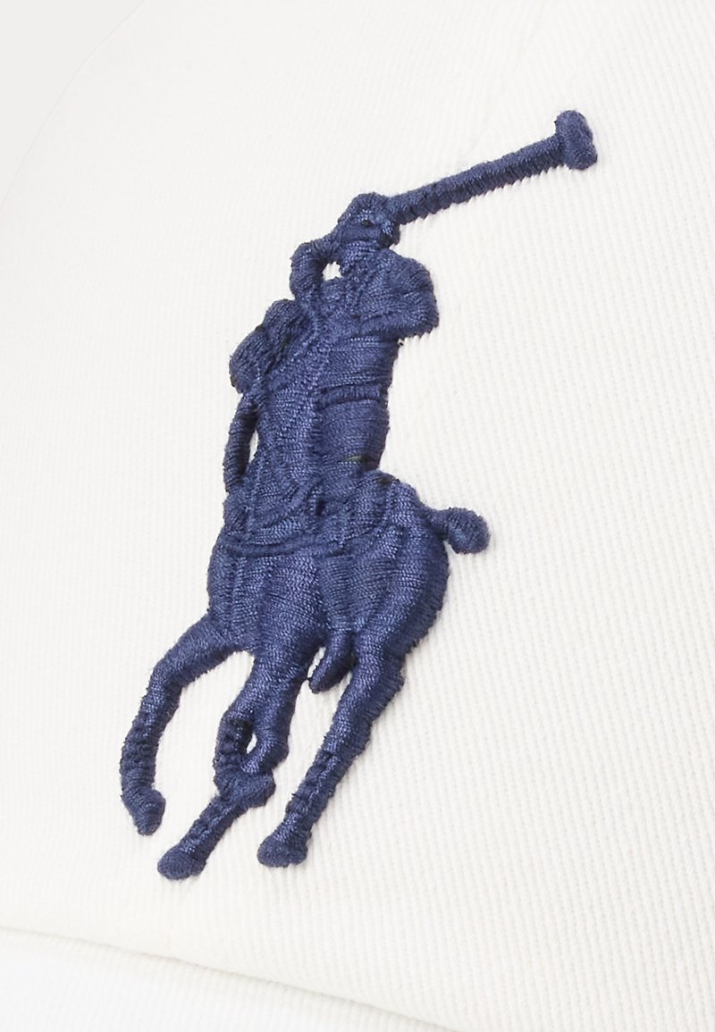 Cappello bianco con un prominente design ricamato di un giocatore di polo e un cavallo in blu navy, che mostra texture e cuciture dettagliate.