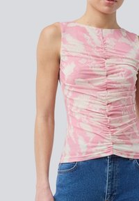 Fitted sleeveless top in pink with a white abstract pattern. Features gathered detailing along the front and a crew neckline.