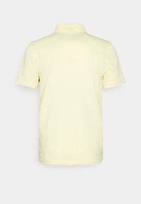 Polo tričko z lehkého žlutého materiálu s krátkými rukávy a klasickým límečkem. Má jednoduchý design bez viditelných vzorů nebo akcentů.