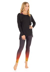 Musta pitkähihainen paita, johon on yhdistetty liukuväriset oranssit ja keltaiset legginssit. Legginsseissä on sileä pinta ja ne istuvat tiukasti.