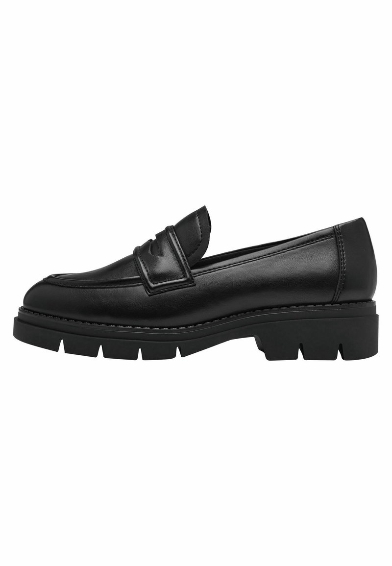 Mocassin en cuir noir avec une semelle épaisse et texturée. Il présente un design brodé subtil et une sangle décorative sur le devant.