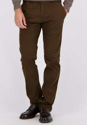 Bruine katoenbroek met rechte snit, voorzien van zijzakken en een gladde textuur. Draagt met zwarte leren schoenen.