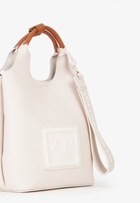 Borsa a tracolla in pelle con texture crema e manici marroni, etichetta embossata "N° 73 Venezia" e tracolla removibile con testo bianco.