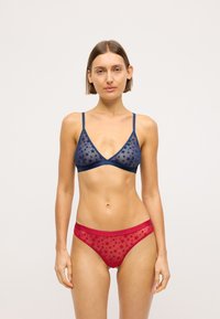 Tumes laheline bralette tähistaevaga ja õhukeste rihmadega, koos punaste läikivate aluspükstega, millel on sobiv tähistaevas ja elastne vöökoht.