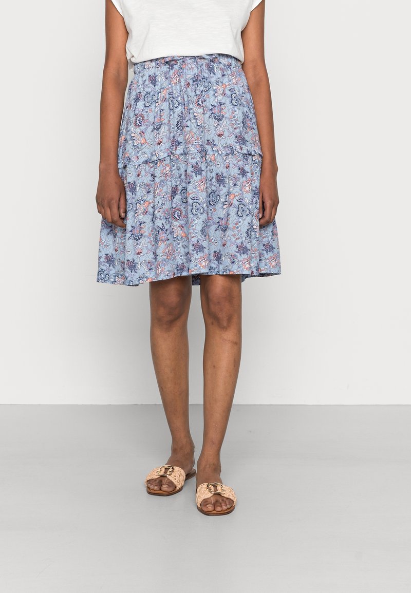 Blue floral skirt with tiered design, featuring pink and white patterns. Paired with tan slip-on sandals adorned with a gold buckle.