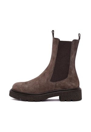 Bota chelsea de ante marrón con paneles laterales elásticos oscuros, pestañas para tirar y una suela de goma negra texturizada. Acabado suave con puntera redondeada.