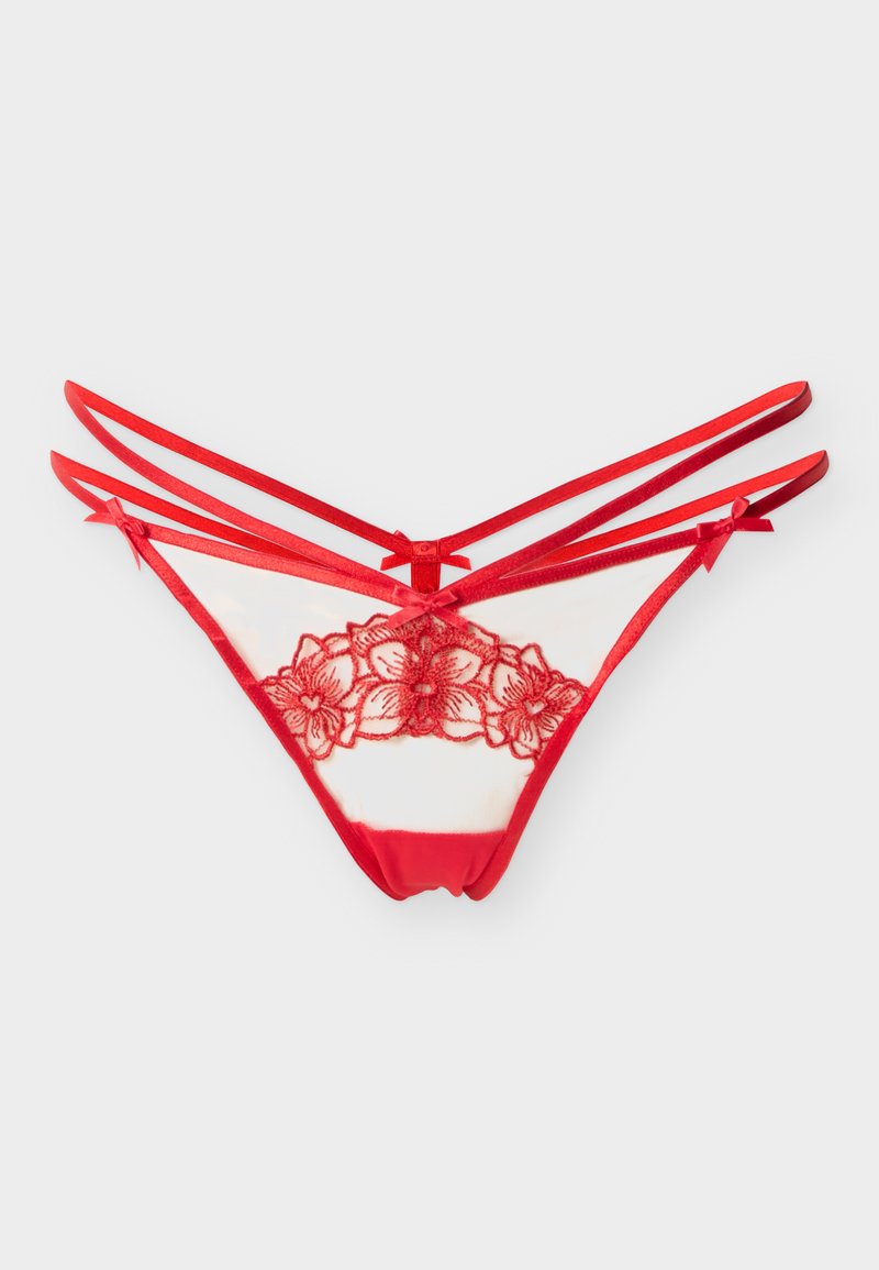 Bas de lingerie en dentelle rouge à bretelles avec broderies florales et petits nœuds sur un fond uni.