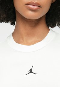 Λευκό βαμβακερό μπλουζάκι με στρογγυλή λαιμόκοψη, που διαθέτει μαύρο κεντημένο λογότυπο Jumpman στο στήθος και λείες υφές υφάσματος.