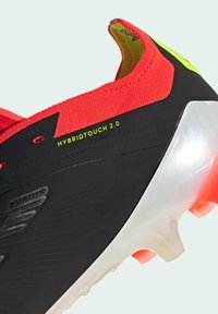 Scarpino da calcio nero e rosso con un design elegante, caratterizzato da una tomaia texturizzata, suola trasparente e dettaglio verde neon "HYBRIDTOUCH 2.0".