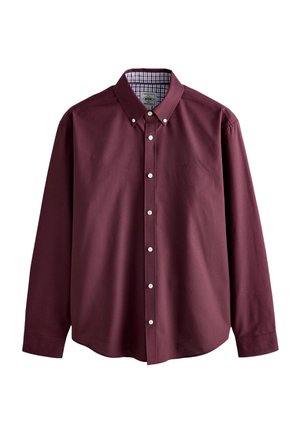 Chemise à manches longues couleur bordeaux avec col boutonné et boutons blancs, dotée d'une doublure intérieure à carreaux sur le col.