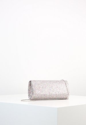 Mała prostokątna srebrna błyszcząca torebka kopertowa z cienkim łańcuszkiem, spoczywająca na białej powierzchni na tle jednolitego tła.