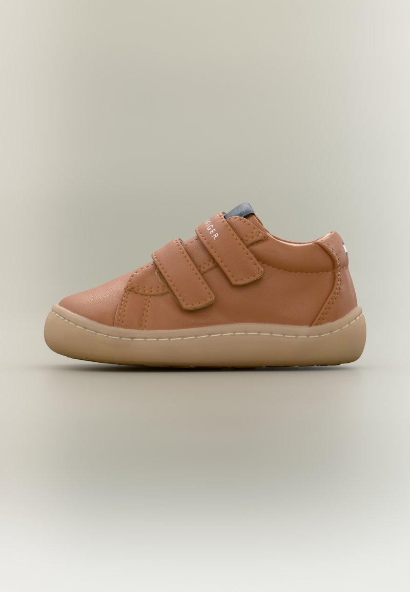 Ταμπά δερμάτινο αθλητικό παπούτσι με δύο ιμάντες βέλκρο, στρογγυλή μύτη και ελαφριά καουτσούκ σόλα. Διαθέτει ελάχιστη ραφή και μικρή λεπτομέρεια στη φτέρνα.