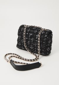 Borsa a mano nera con paillettes e design trapuntato, dotata di una tracolla in metallo dorato e un accento in pelle nera testurizzata sulla tracolla.