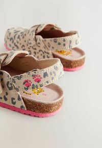 Sandales imprimées léopard avec une semelle en liège, un fond en caoutchouc rose et une sangle ajustable ; présentent une empreinte de patte et un chat en dessin animé sur la semelle intérieure.