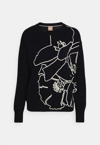 Czarny sweter z dzianiny z dużym białym abstrakcyjnym wzorem kwiatowym na przodzie i okrągłym dekoltem.