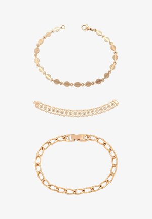 Három arany karkötő: fent csavart ovális szemekkel, középen apró gyöngyökkel és beágyazott kristályokkal, lent nagy láncszemekkel és csattal.
