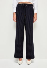 Marineblaue weit geschnittene Hose mit vertikalen Streifen, ausgestattet mit einem Kordelzugbund, Fronttaschen und einem genähten Design für zusätzliche Textur.