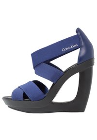 Sandales à talons compensés bleu marine avec des sangles élastiques, design à bout ouvert, et une plateforme noire contrastante. Elles présentent un talon courbé et un détail de logo.