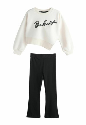 Hvid cropped sweatshirt med lange ærmer med teksten "Baker" og sort bånddetalje kombineret med sorte vida bukser med elastisk talje.