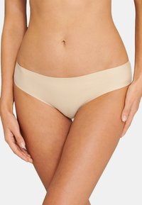 Culottes beige sans couture avec une texture lisse et une large ceinture élastique, conçues pour le confort et une visibilité minimale sous les vêtements.