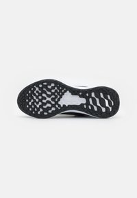Suela de zapatilla en blanco y negro con un patrón de agarre texturizado y el logotipo "Nike Running" grabado en el centro, debajo del arco.