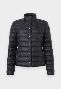 Veste légère matelassée noire avec col montant, boutons-pression à l'avant, poches latérales et étiquette de marque sur la poitrine et la manche.