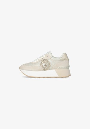 Zapatilla blanca con parte superior de ante y malla, decorada con purpurina. Suela gruesa con un acento decorativo en el talón.