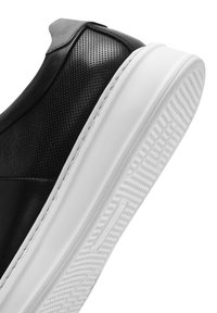 Sneaker in pelle nera forata con punta liscia, suola in gomma bianca a contrasto e pattern texturizzato per una migliore aderenza.