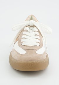 Baskets en suède beige et blanc avec de larges lacets blancs noués en nœud, semelle en gomme arrondie, présentées de face sur un fond blanc.