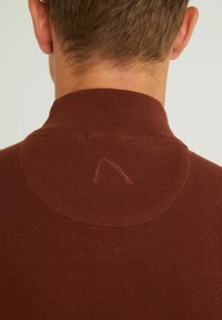 Brązowy sweter dziany z wysokim kołnierzem. Posiada okrągły wzór przy dekolcie oraz subtelny haft na środku pleców.