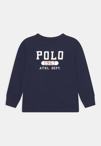 Marinblus med långa ärmar och vit och röd text som säger "POLO 1967 ATHL. DEPT." på ryggen, rund hals, ribbade muddar.