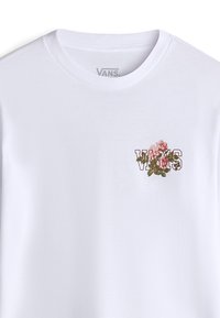 Vit bomulls t-shirt med en blomstrande "VANS" grafik på bröstet. Rund halsringning och korta ärmar. Slät textur.