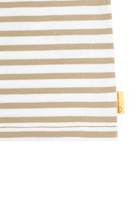 Tejido a rayas en beige y blanco, con una textura suave. El borde tiene costuras visibles, con una etiqueta amarilla en el lateral para la marca.