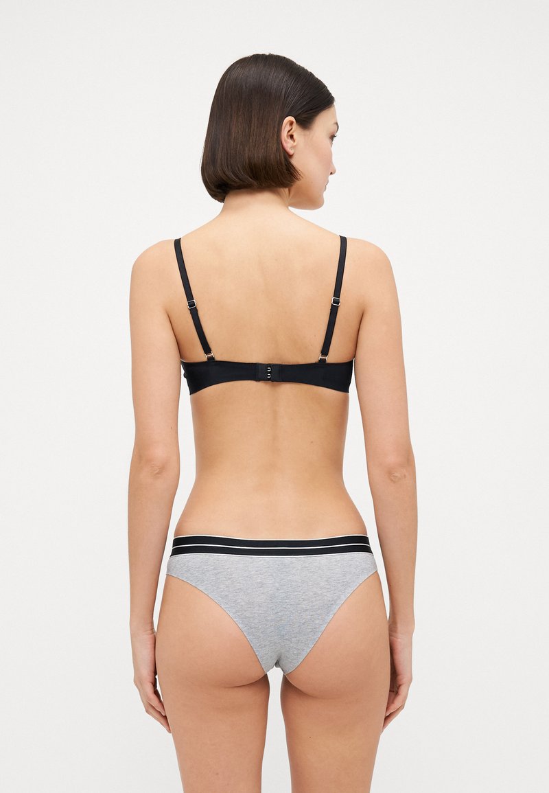 Soutien-gorge sans fil noir avec bretelles ajustables et agrafe. Sous-vêtements gris avec taille noire, fabriqués dans un tissu doux et extensible.
