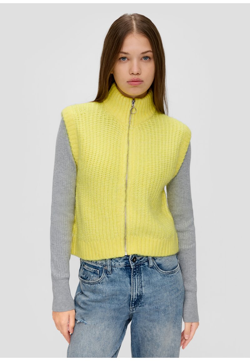Strick-Crop-Top in leuchtendem Gelb mit hohem Kragen und silbernem Reißverschluss. Graue lange Ärmel sind sichtbar. Texturiertes, geripptes Material.