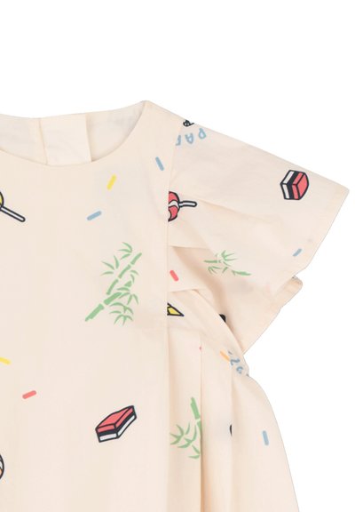 Tissu crème avec imprimés de bonbons colorés, snacks, feuilles de bambou et manches papillon sur une robe d'enfant.