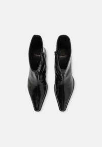Bocanci negri cu vârf ascuțit și un finisaj din piele lucioasă, având fermoare pe lateral și un design elegant, potriviți pentru stilurile moderne de încălțăminte.