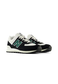 Une paire de baskets New Balance 574 noires, blanches et vertes avec des détails en mesh et en daim, placées côte à côte sur un fond blanc.