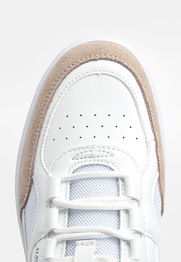 Baskets en cuir blanc avec des accents en suède beige, comportant des panneaux en mesh, une pointe perforée et des lacets blancs plats sur une semelle texturée.